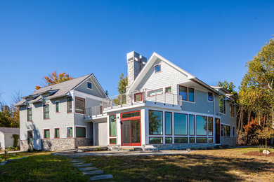 Foto della facciata di una casa grande grigia moderna a due piani con rivestimenti misti e tetto a capanna