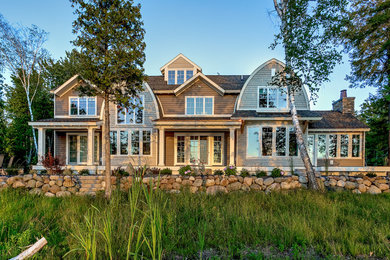 Ejemplo de fachada de casa marrón costera de dos plantas con revestimientos combinados, tejado a dos aguas y tejado de teja de madera
