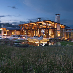 Inspiration for a rustic brown two-story glass house exterior remodel in Denver with a shed roof and a metal roof