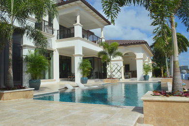 Large tuscan white two-story stucco exterior home photo in Miami with a shingle roof