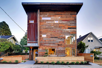 Imagen de fachada marrón contemporánea de tres plantas con revestimiento de madera y tejado plano