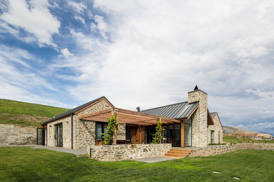 Immagine della villa grande multicolore contemporanea a un piano con rivestimento in pietra, tetto a capanna e copertura in metallo o lamiera