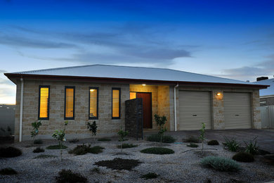 Diseño de fachada de casa beige actual de tamaño medio de una planta con revestimiento de hormigón, tejado a cuatro aguas y tejado de metal