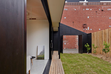 This is an example of a black contemporary two floor house exterior in Melbourne with wood cladding.