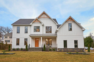 Imagen de fachada de casa blanca clásica renovada grande de dos plantas con revestimiento de aglomerado de cemento, tejado a dos aguas y tejado de teja de madera