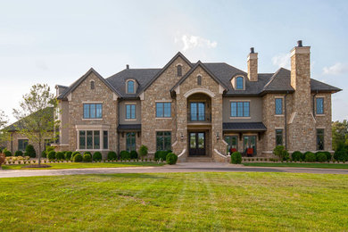 Huge elegant beige two-story stone exterior home photo in Other with a hip roof