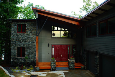 Modelo de fachada gris minimalista grande de tres plantas con revestimientos combinados y tejado de un solo tendido