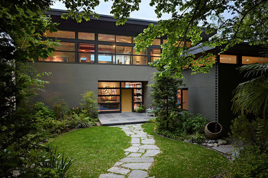 Стильный дизайн: двухэтажный, коричневый частный загородный дом среднего размера в современном стиле с облицовкой из цементной штукатурки, односкатной крышей и металлической крышей - последний тренд