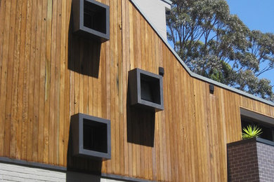 Imagen de fachada de casa gris actual de tamaño medio de tres plantas con revestimiento de madera, tejado a dos aguas y tejado de metal