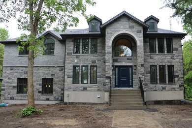Inspiration for a gray two-story stone house exterior remodel in Other with a shingle roof
