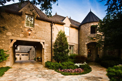 Large traditional beige two-story stone house exterior idea in Other with a hip roof and a shingle roof