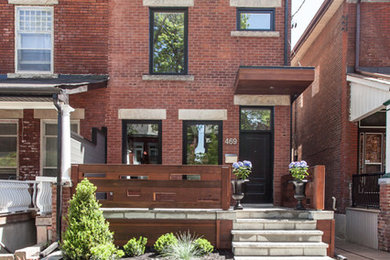 Inspiration for a medium sized and red contemporary brick house exterior in Toronto with three floors and a pitched roof.