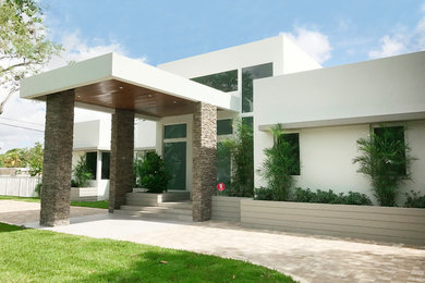 This is an example of a medium sized and white modern bungalow render detached house in Miami with a flat roof.