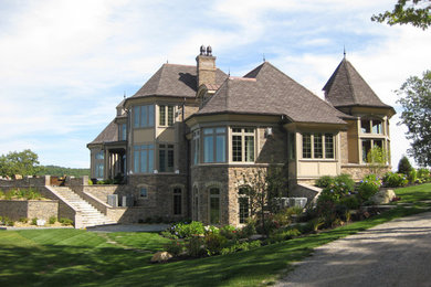 Aménagement d'une très grande façade de maison marron craftsman en pierre à deux étages et plus avec un toit à deux pans et un toit en tuile.