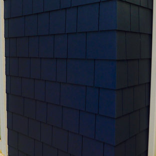 Modelo de fachada de casa azul, tradicional, de tamaño medio, de dos plantas, con revestimiento de aglomerado de cemento, tejado de teja de madera y tejado a dos aguas
