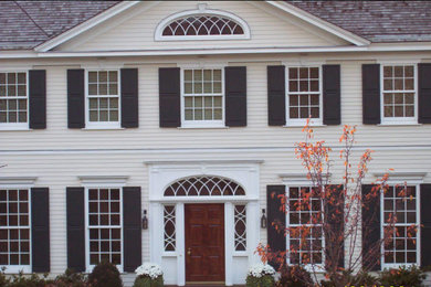 Inspiration for a large white three-story vinyl gable roof remodel in New York