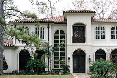 Mid-sized elegant beige two-story stone house exterior photo in Houston with a hip roof and a tile roof