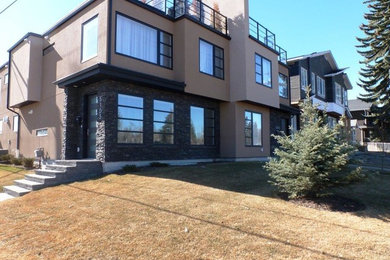 Large traditional beige two-story stucco exterior home idea in Calgary