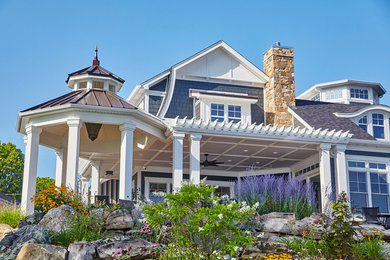 Large traditional blue two-story vinyl exterior home idea in Other with a clipped gable roof
