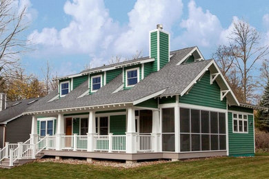 This is an example of a medium sized and green traditional two floor house exterior in Chicago with wood cladding and a pitched roof.