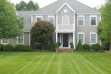 Large elegant gray two-story vinyl house exterior photo in Boston with a clipped gable roof and a tile roof