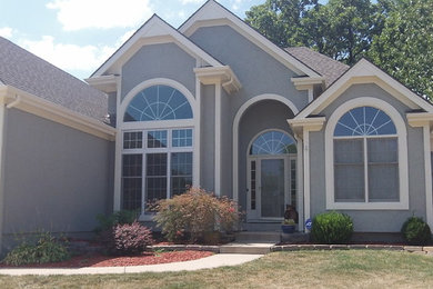 Example of a mid-sized classic gray two-story stucco house exterior design in Kansas City with a clipped gable roof and a mixed material roof