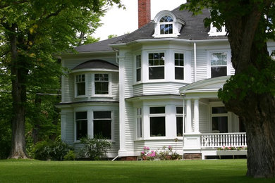 This is an example of a large and white traditional house exterior in Boston with three floors.