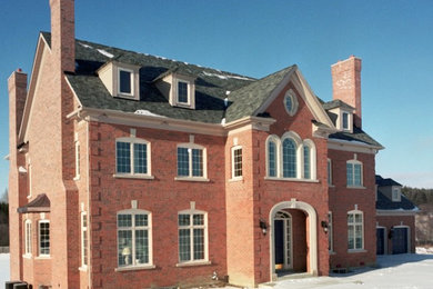 Imagen de fachada de casa roja tradicional grande de dos plantas con revestimiento de ladrillo