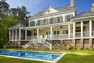 Ejemplo de fachada beige tradicional grande de dos plantas con revestimientos combinados y tejado a cuatro aguas