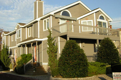 This is an example of a large and brown coastal two floor house exterior in Philadelphia with wood cladding.