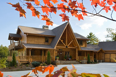 Immagine della villa grande marrone rustica a due piani con rivestimento in legno, tetto a padiglione e copertura a scandole