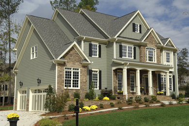 Ejemplo de fachada de casa verde de estilo americano de tres plantas con revestimiento de vinilo