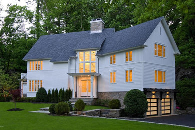Réalisation d'une façade de maison blanche champêtre de taille moyenne et à niveaux décalés avec un revêtement mixte, un toit à deux pans et un toit en shingle.