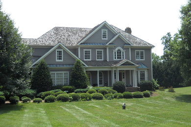Modelo de fachada de casa gris tradicional grande de dos plantas con revestimiento de vinilo, tejado a la holandesa y tejado de teja de madera