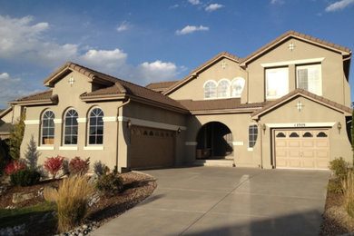 Large tuscan beige two-story stucco house exterior photo in Denver with a hip roof and a tile roof