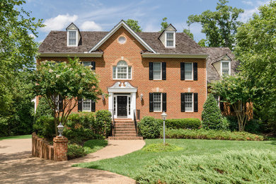 Foto della facciata di una casa grande rossa classica a due piani con rivestimento in mattoni