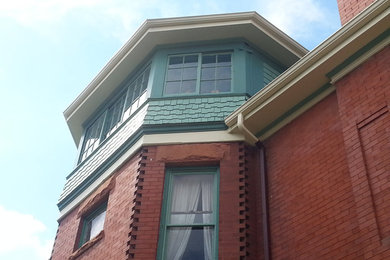 Modelo de fachada marrón de tres plantas con revestimientos combinados