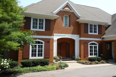 Large traditional brown two-story wood exterior home idea in Grand Rapids with a hip roof