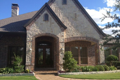 Large beige three-story stone exterior home idea in Dallas