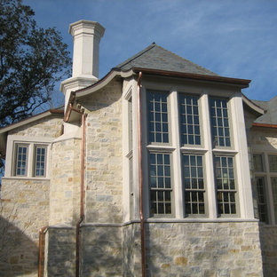 Large elegant beige two-story stone house exterior photo in Houston with a hip roof and a shingle roof