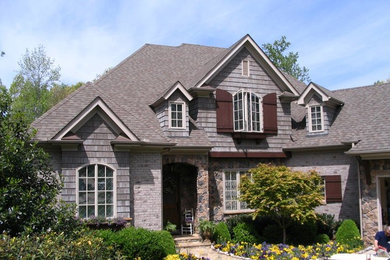 Imagen de fachada de casa gris tradicional renovada grande de dos plantas con revestimiento de piedra, tejado a dos aguas y tejado de teja de madera