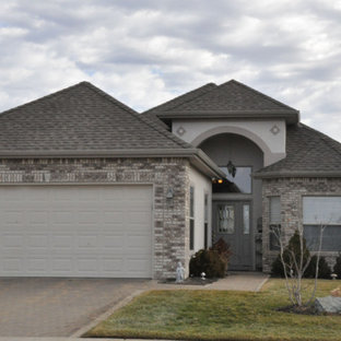 Mid-sized traditional gray two-story brick exterior home idea in Other with a hip roof