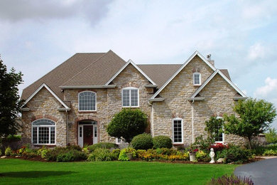 Large traditional beige two-story stone exterior home idea in Chicago with a shingle roof