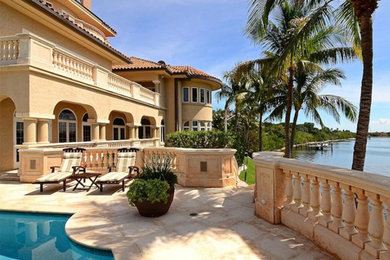 Large tuscan beige two-story stucco exterior home photo in Miami with a tile roof