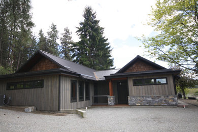 Foto de fachada de casa de una planta con revestimientos combinados y tejado de metal
