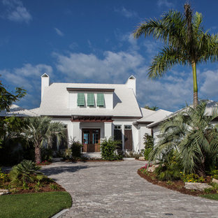 Foto della facciata di una casa piccola bianca tropicale a due piani con rivestimento in stucco e tetto a padiglione