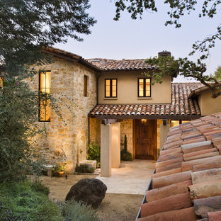Example of a tuscan two-story stone exterior home design in San Francisco with a tile roof