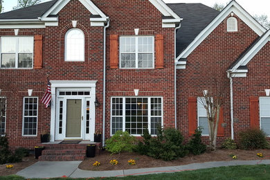Inspiration for a large timeless red two-story brick gable roof remodel in Charlotte
