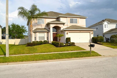 Mid-sized transitional beige two-story stucco house exterior photo in Tampa with a hip roof and a shingle roof