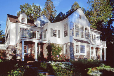 Modelo de fachada blanca tradicional grande de dos plantas con revestimientos combinados y tejado a dos aguas